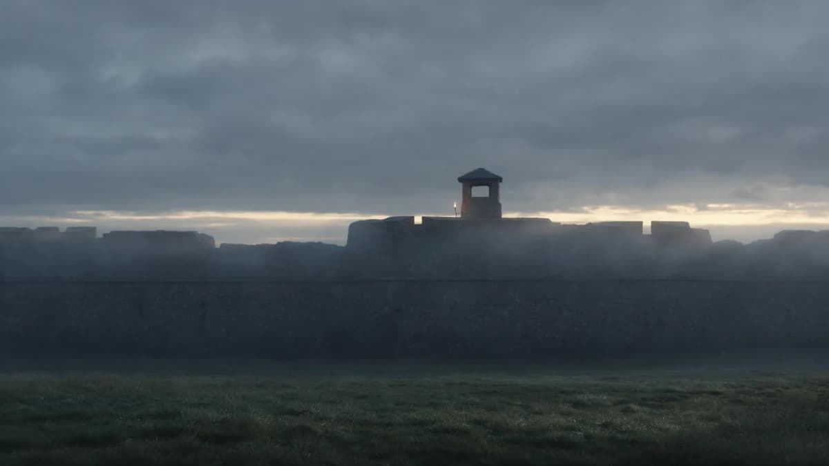 Misty stone fortress wall at dawn under a heavy overcast sky